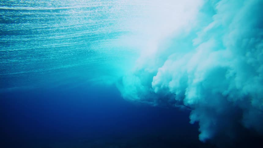 Underwater view of the ocean during the day and a tubular wave with foam passing by