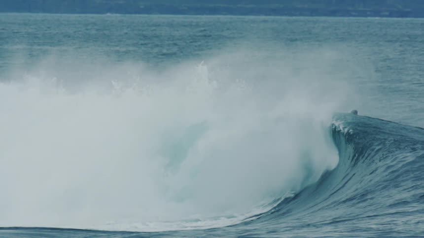 A man rides a wave on his surfboard