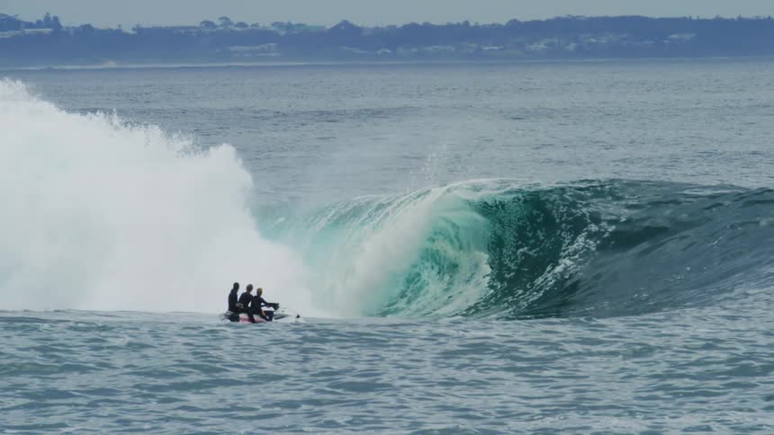 People ride a jet ski into a wave