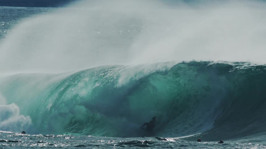 Surfers in the ocean with one of them riding a tubular wave
