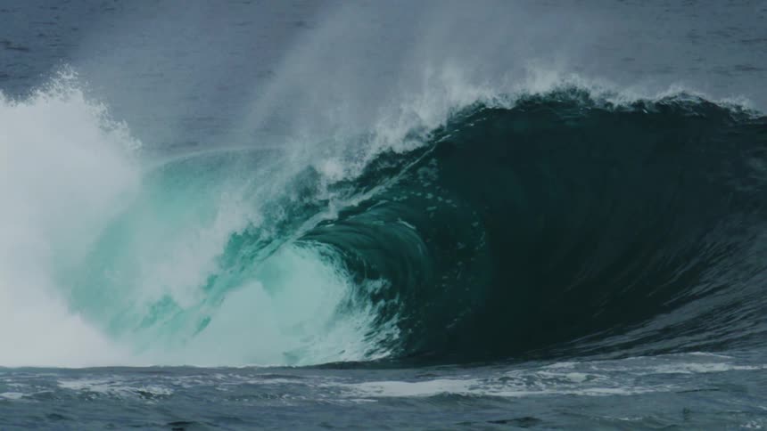 Large wave breaks filling the air with spray during the daytime