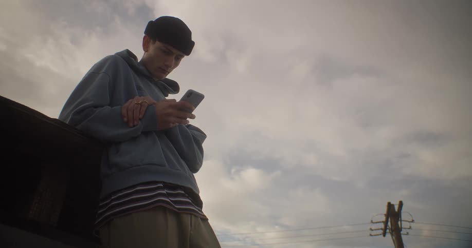 Man in an outdoor environment typing on a smartphone
