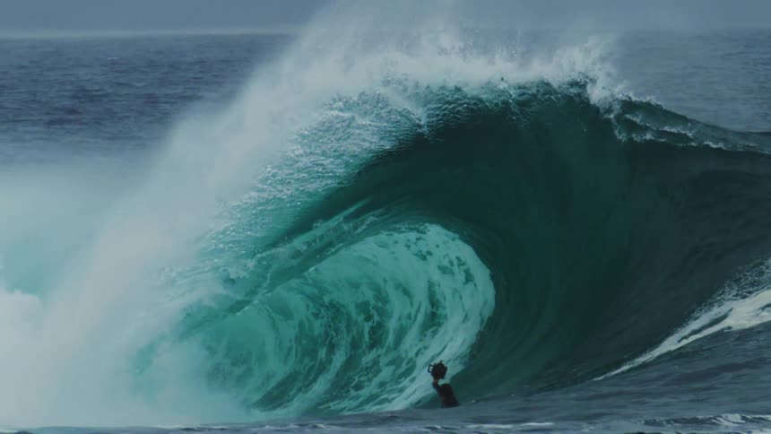 Cameraman in the ocean next to a tubular wave