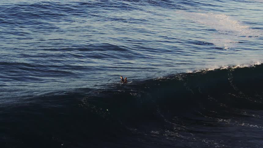 Two surfers in a vast ocean with waves