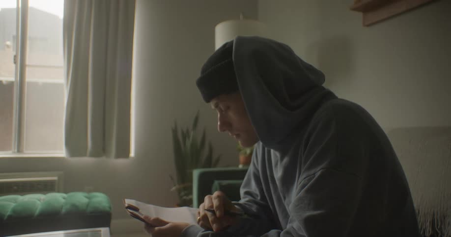 Teenager sits in his living room and considers what else to write