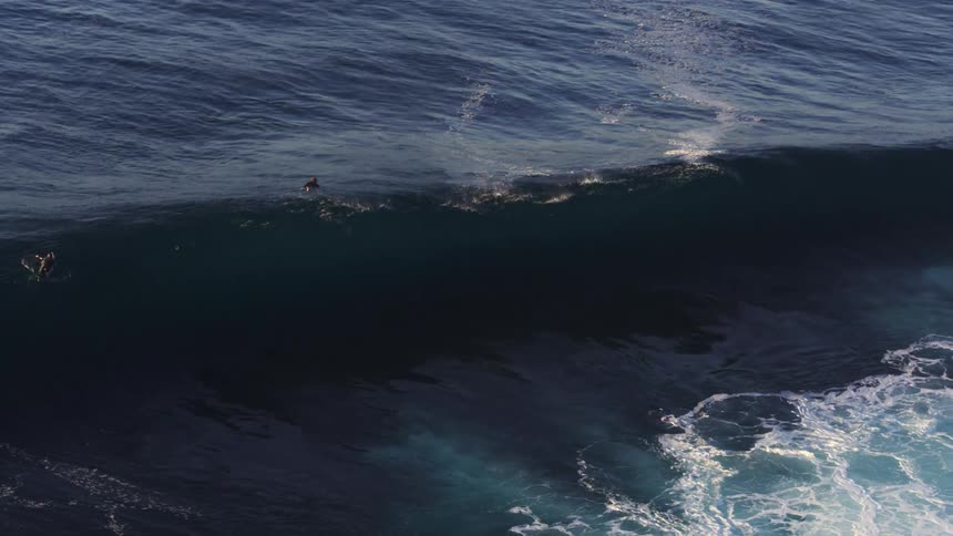 Aerial view of some surfers in the ocean with strong waves