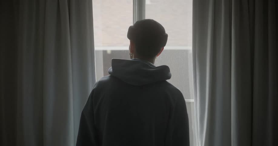 A teenager leans while looking out the window
