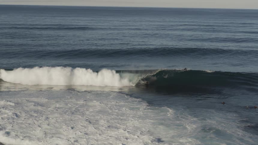 Aerial view of surfers at dawn in a sea with tubular waves
