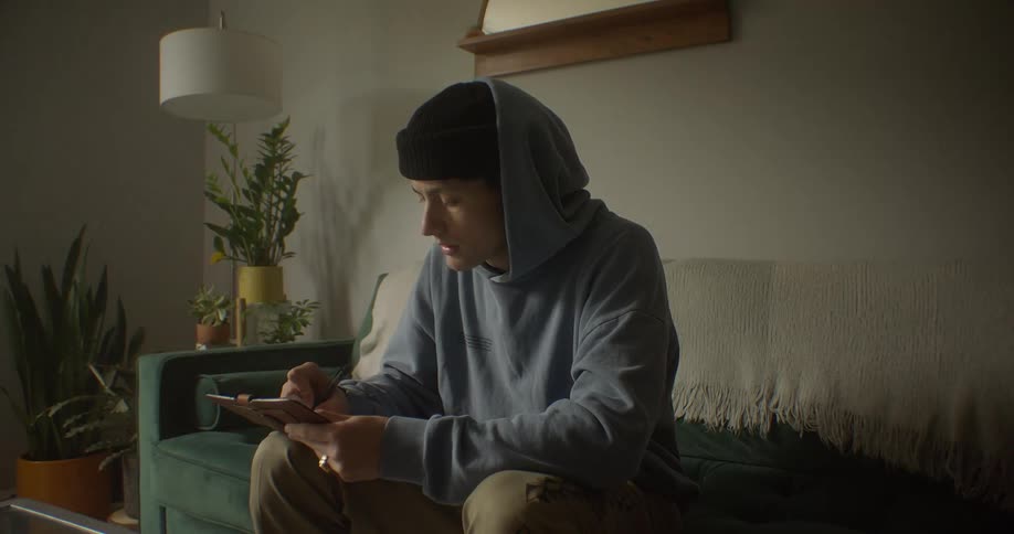 Man writing on a notepad while sitting in a living room