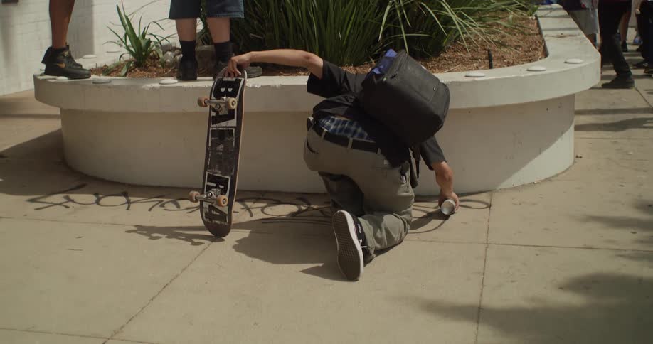 Person holding a skateboard and spray painting a sidewalk