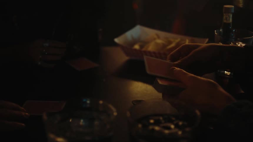 Pair of hands dealing cards from a deck on a bar table