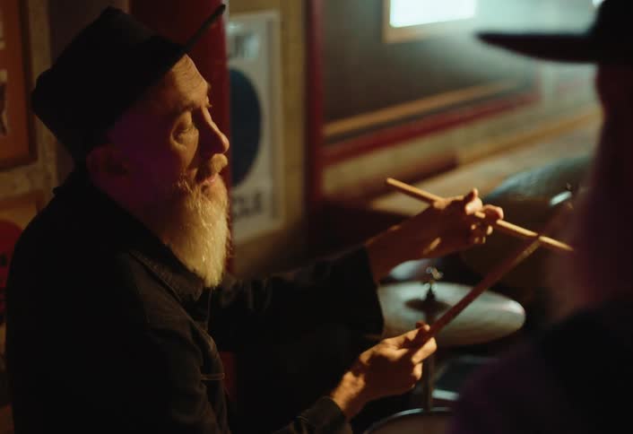 A man talks and plays the drums