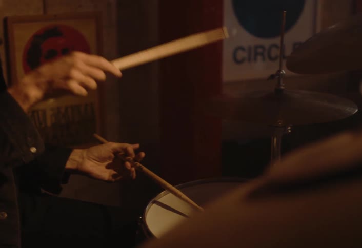 An elderly man is playing drums with a full drum set