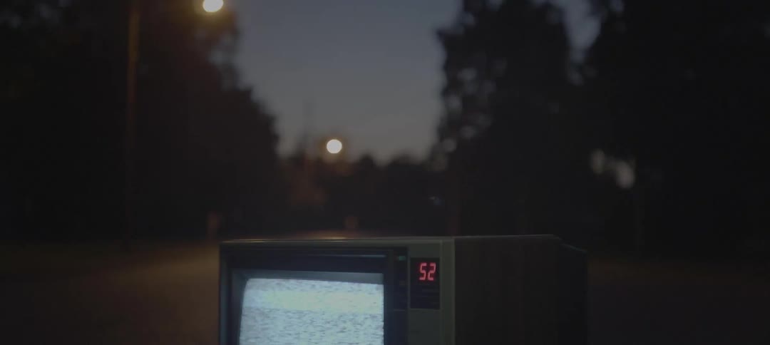 Tv showing static outside on the pavement at night