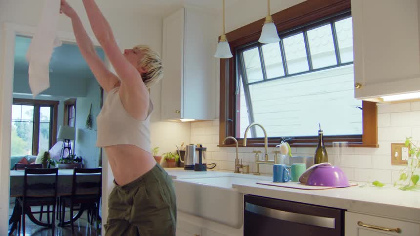 Person dances in the kitchen before drying a cup