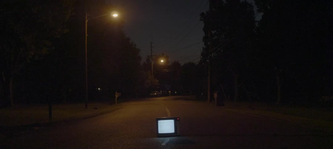Tv flickers static the middle of a street at night