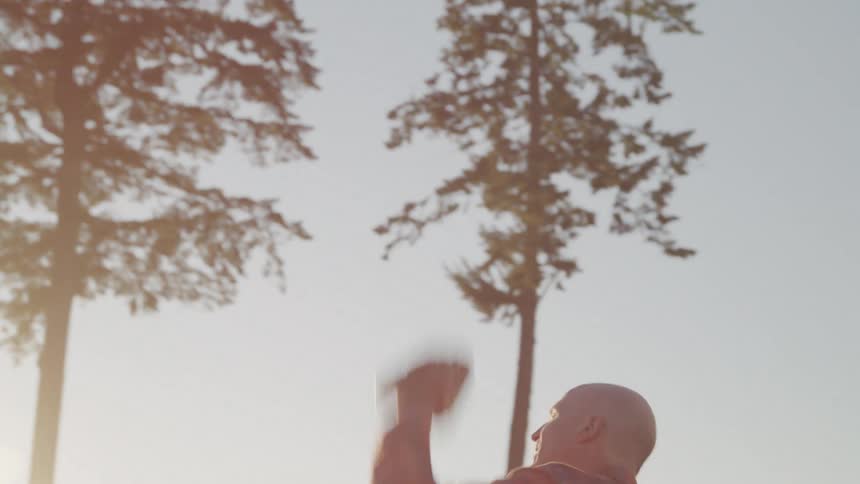 A man plays a game of catch with a baseball while standing outdoors