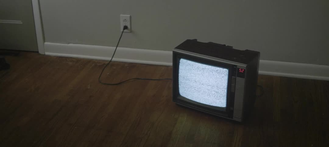 An old tv sets on the hardwood floor displaying static