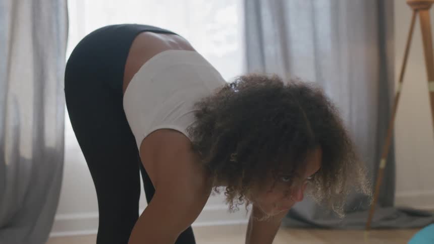 Woman stretches while working out in her home during the daytime