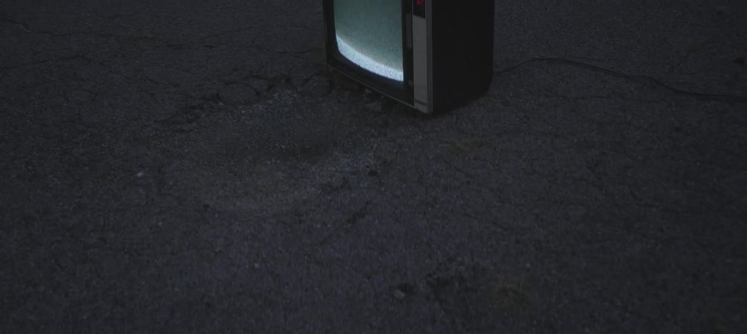 A tv's screen is flickering and rolling while it sits on a street