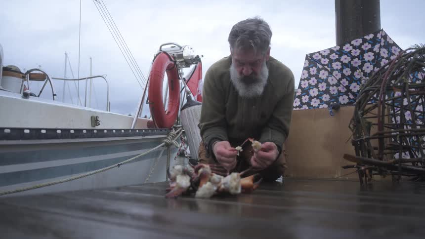 Man on his knees setting up crab baits
