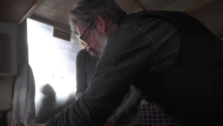 Couple in a kitchen in the cabin of a boat cooking