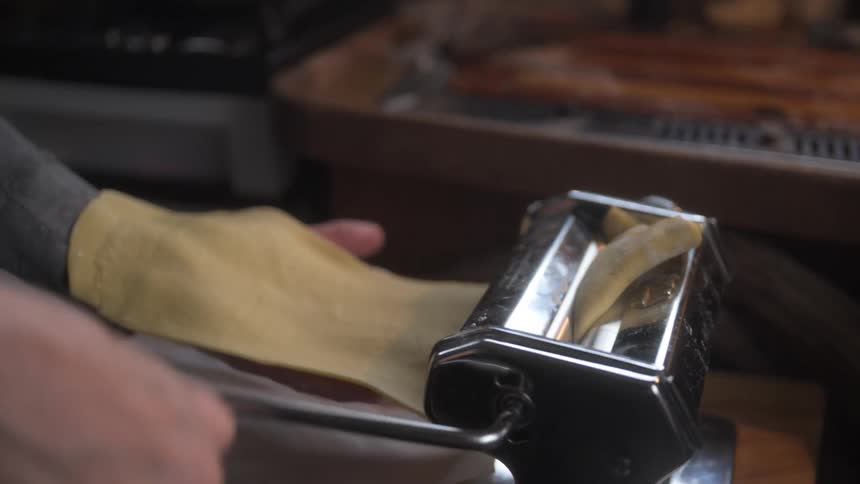 A person is putting a sheet of cough through a pasta machine