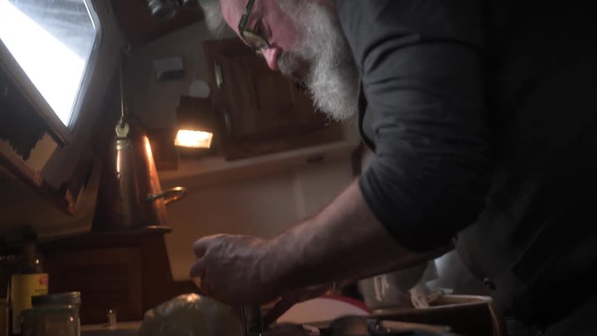 A man and woman are in the kitchen of a boat preparing food
