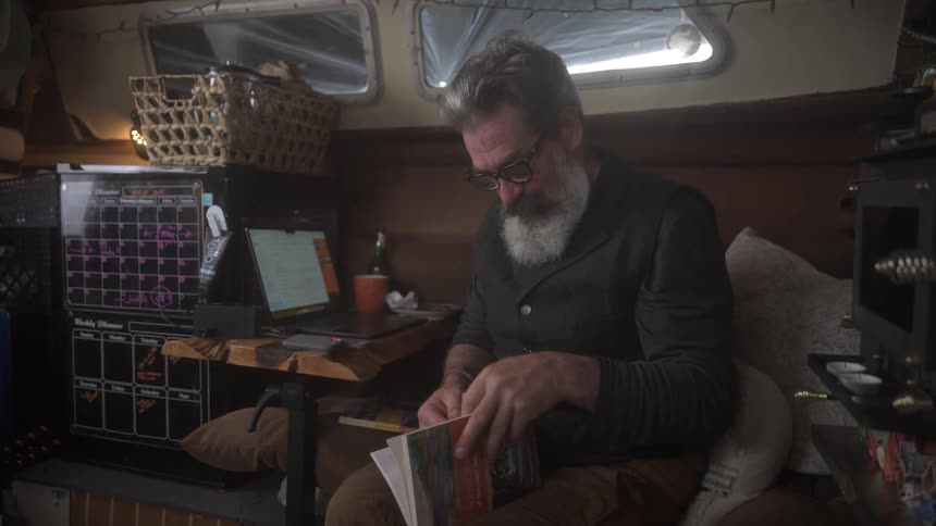 A man is sitting inside a boat looking at a book