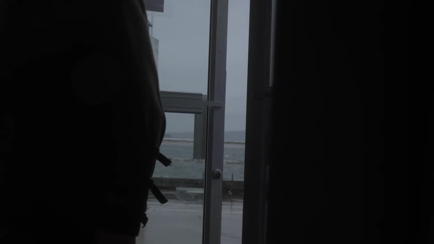 Man entering a door with the sea in the background