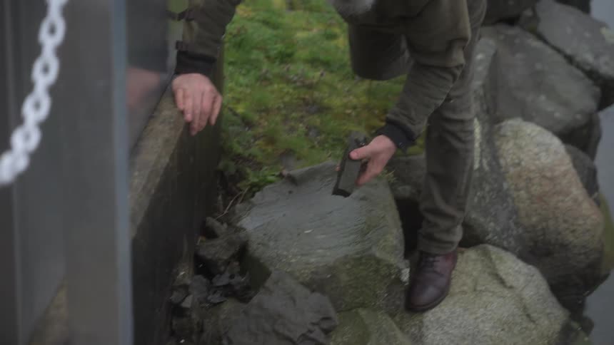 A man picks up a rock by the docks