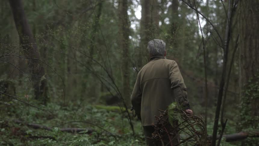 Man walking through a forest with a trap