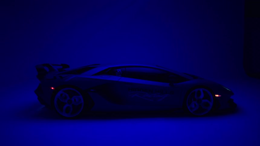 Sports car with aerodynamic design is partially illuminated by blue light
