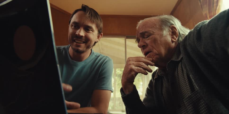 Two men are discussing something on their laptop