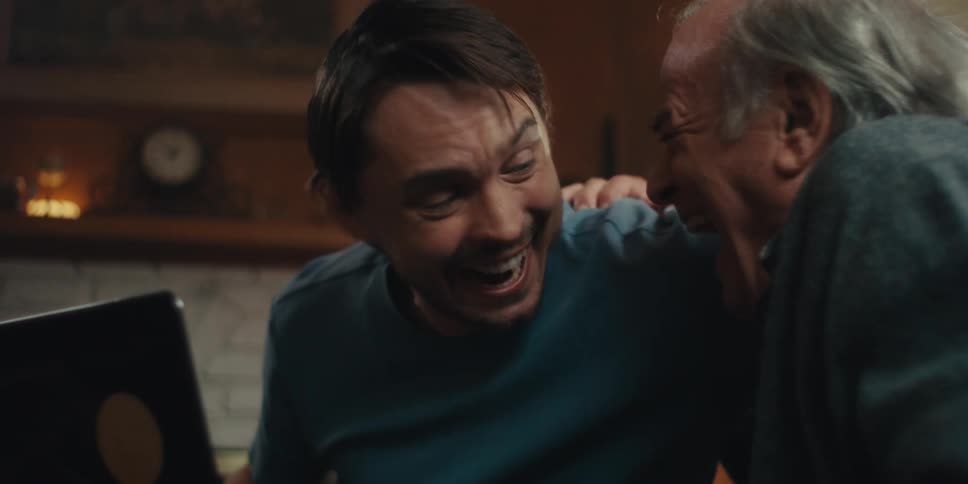 Two men hug while cheering at the laptop