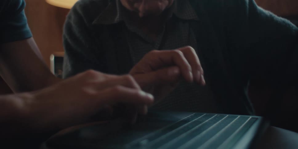 A man talks as another types on the laptop