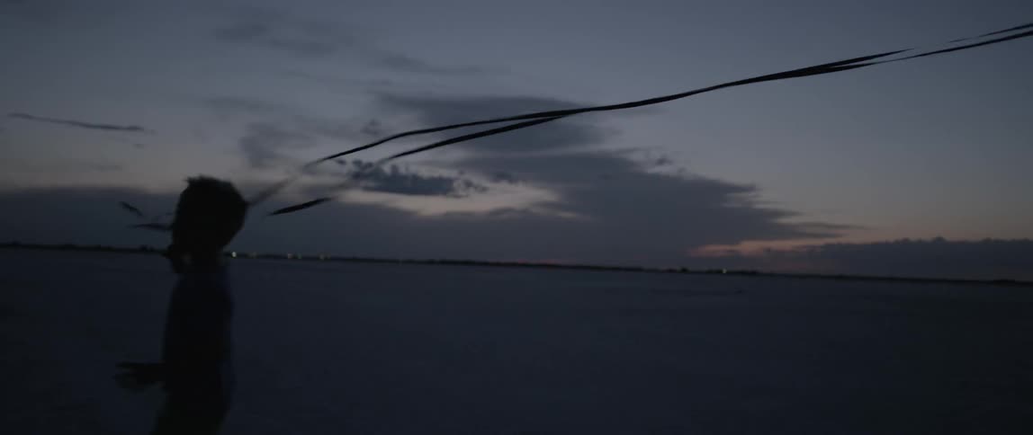 Silhouette of a child trying to catch streamers at sunset