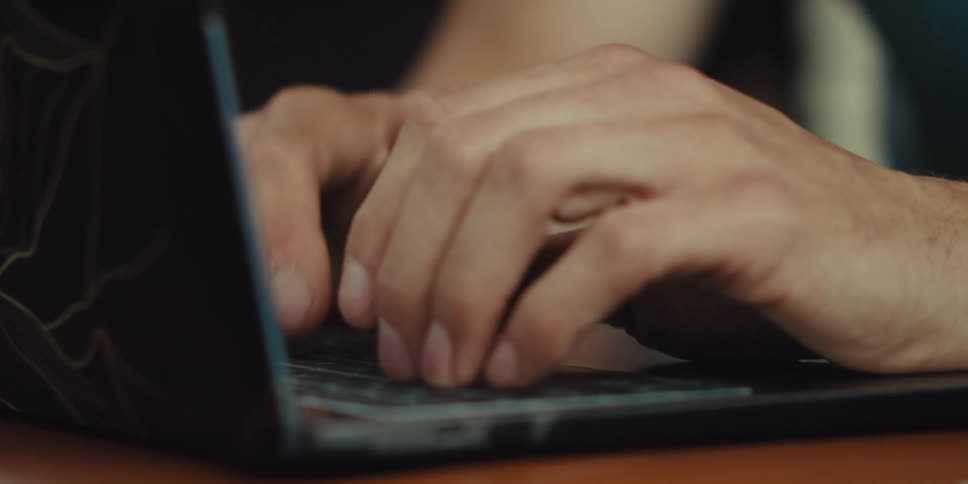 Cheerful man next to an elderly person typing on a laptop