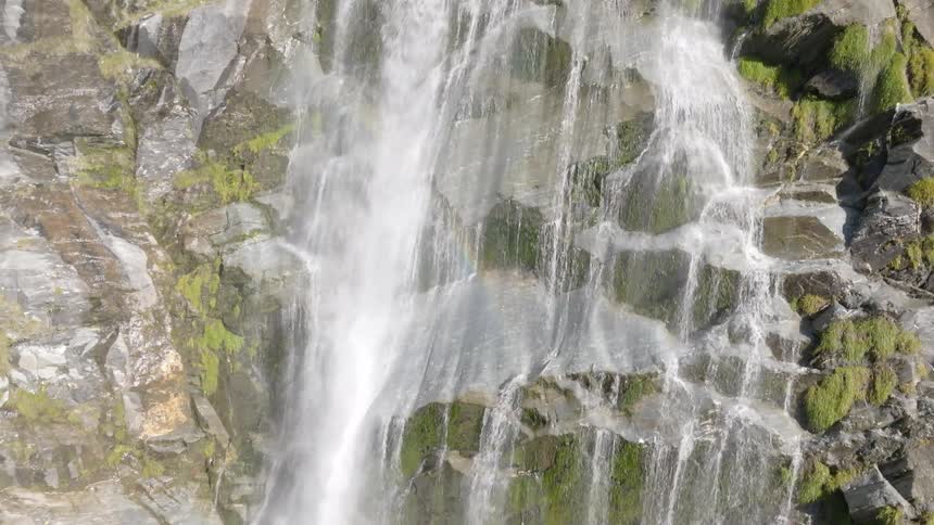 Water cascades powerfully down a steep rocky mountainside in a closeup view highlighting the force of nature