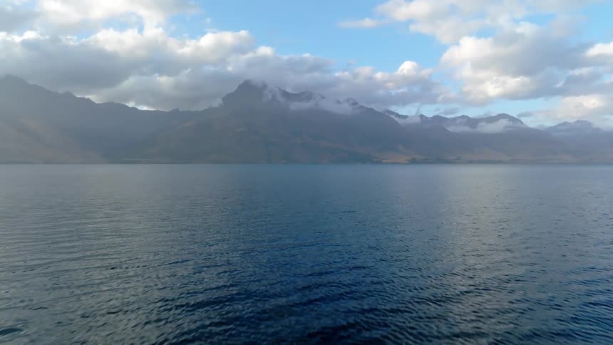 Natural landscape of a calm bar with mountains on the horizon on a day with scattered clouds