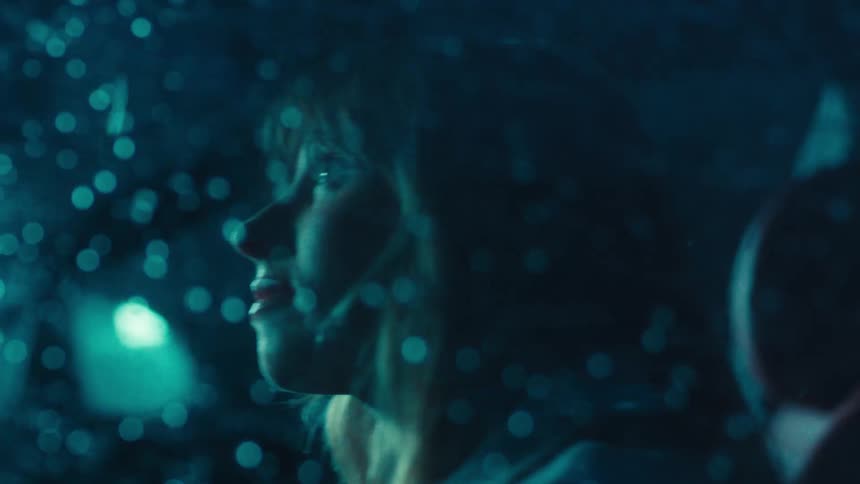 Side portrait of a woman inside a car with a window splashing with rainwater