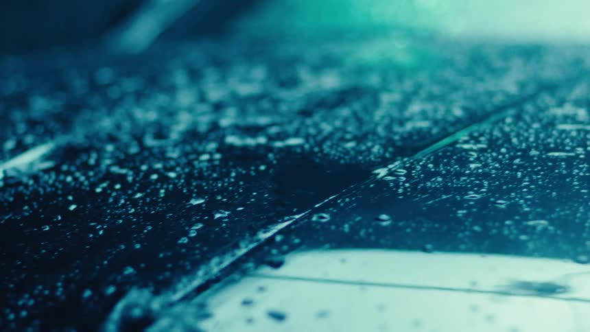 Rainwater dripping onto the surface of a car