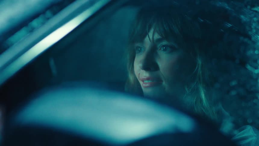 Woman inside the car smiling and while it is raining
