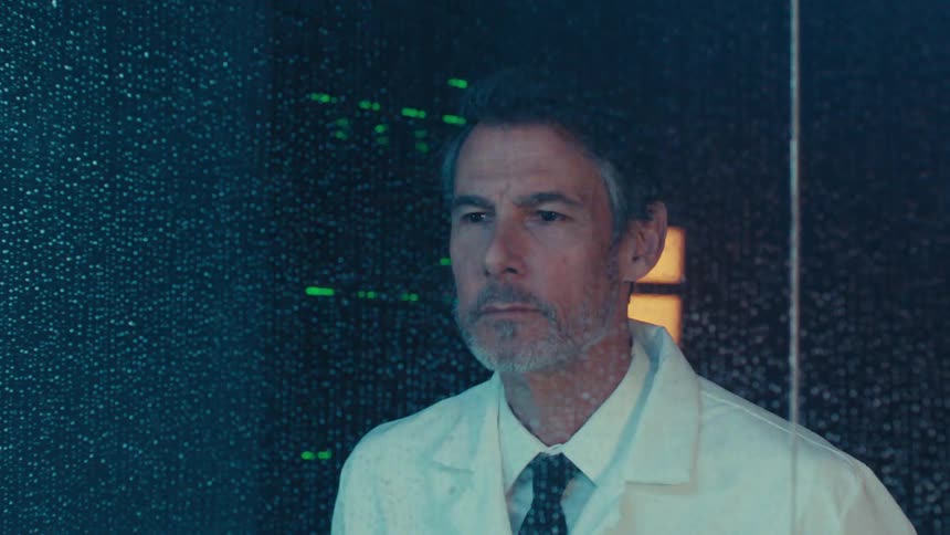 Scientist in tie and white coat looking through a window