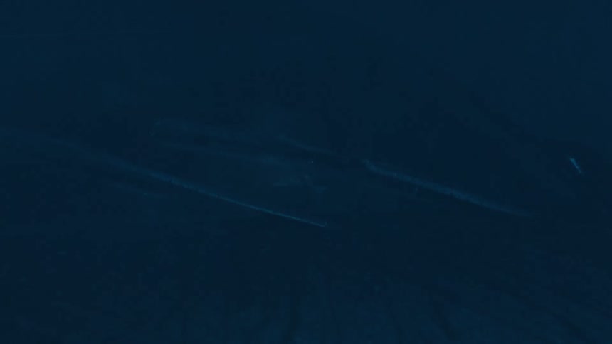 A closeup of a woman sitting in the drivers seat gazing through the windshield as heavy rain pours outside at night