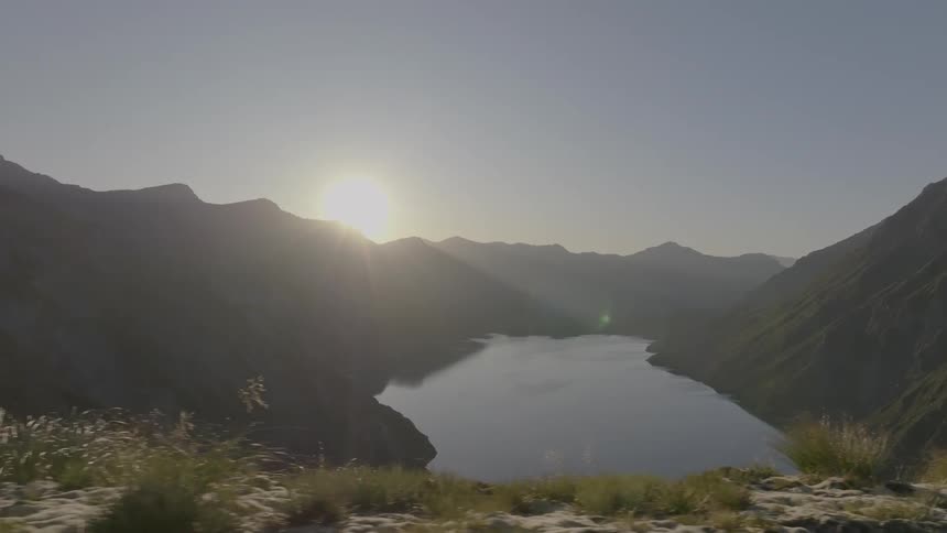 Natural landscape on one side surrounded by mountains and sunrise on the horizon