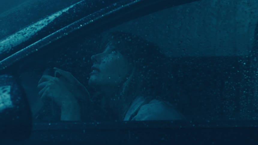 Woman anxiously sitting in her car during a thunderstorm with rain and lighting