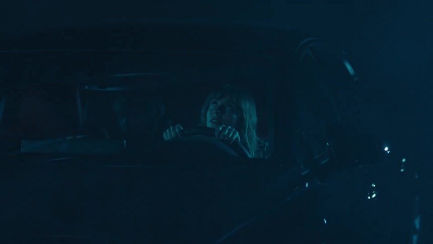 A woman sits in her car looking worried during a major thunderstorm
