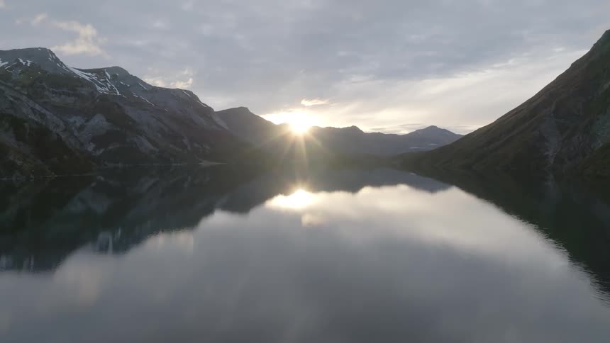 Aerial landscape of sunrise on horizon reflecting in a lake with mountains around