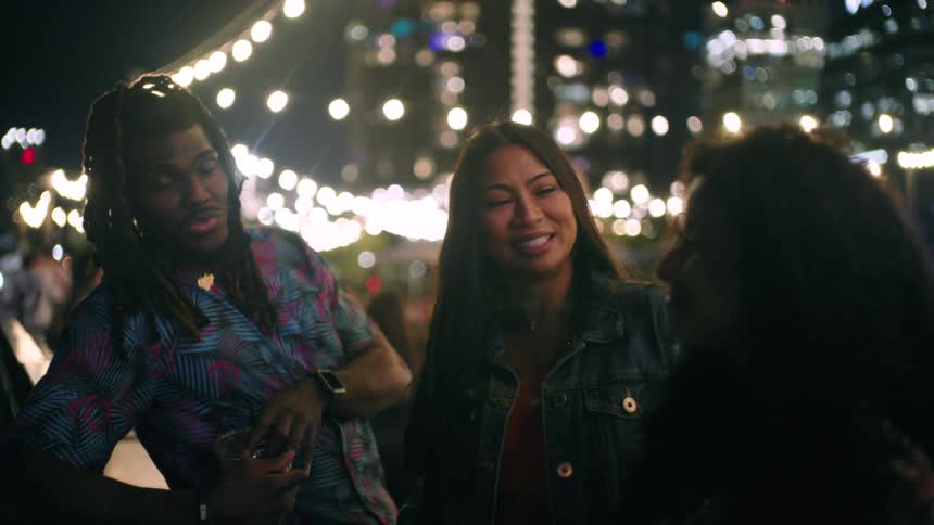 Three friends at an outdoor bar at night talking happily